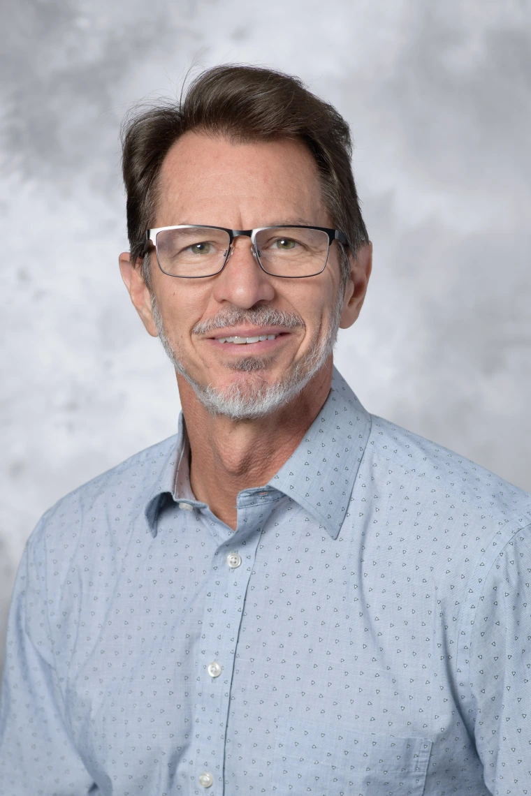 Smiling man wearing glasses and blue button up shirt