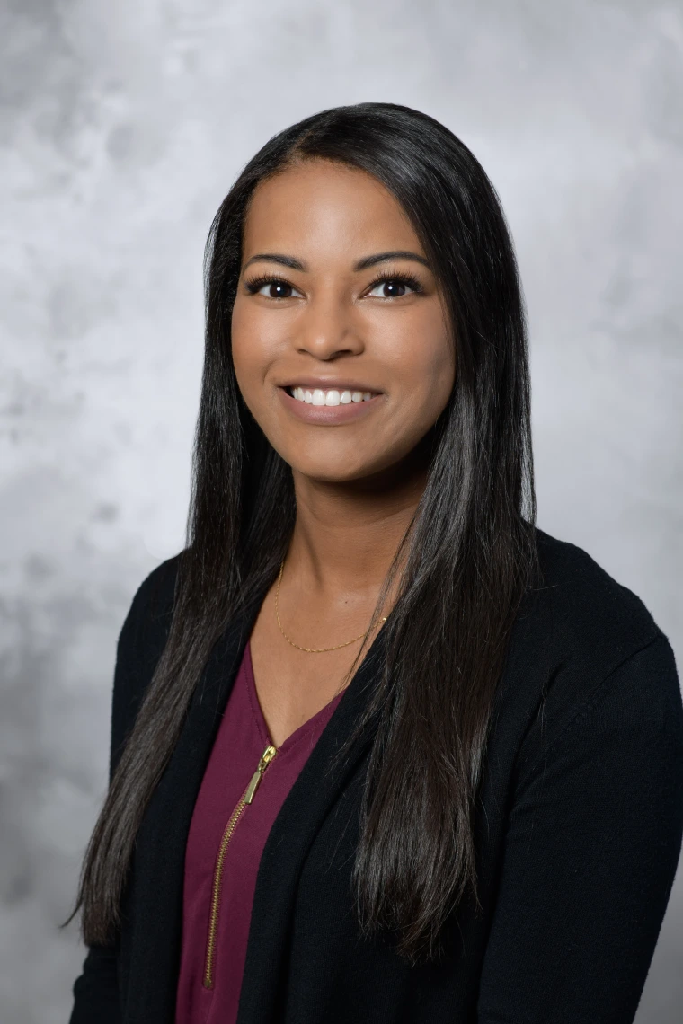 Woman smiling and wearing a maroon blouse and black cardigan